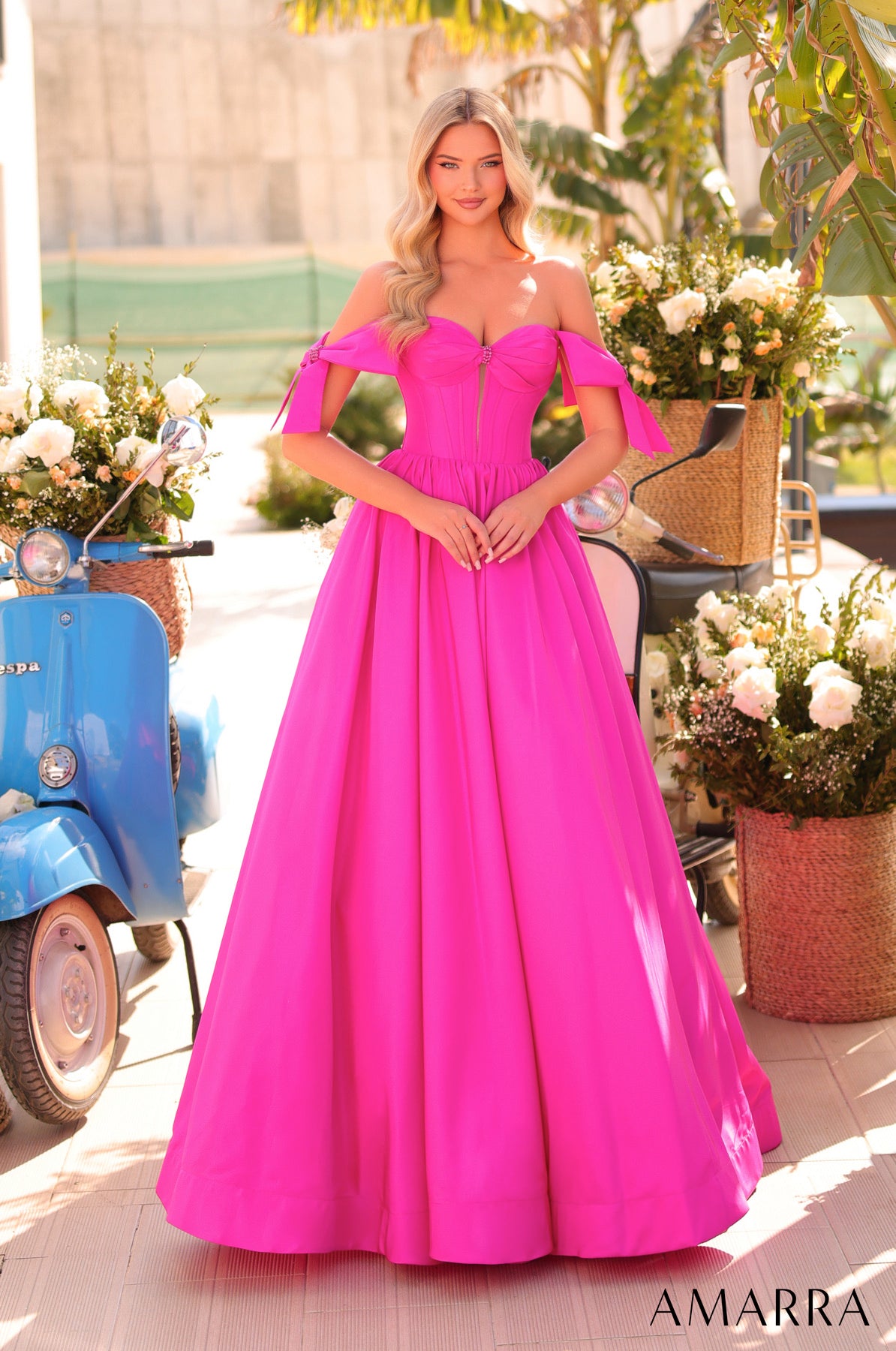 Woman in a bright pink evening gown standing outdoors with flowers and a scooter in the background